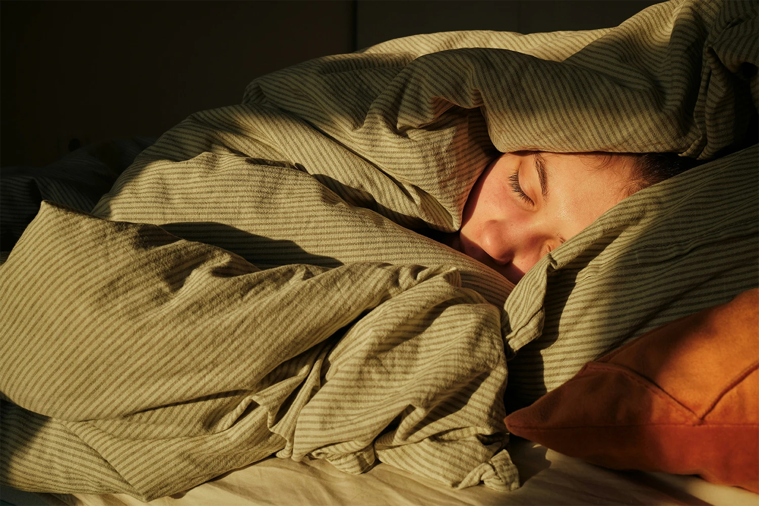 Jugendlicher eingekuschelt in eine Decke, da in der Pubertät ein höheres Schlafbedürfnis besteht.