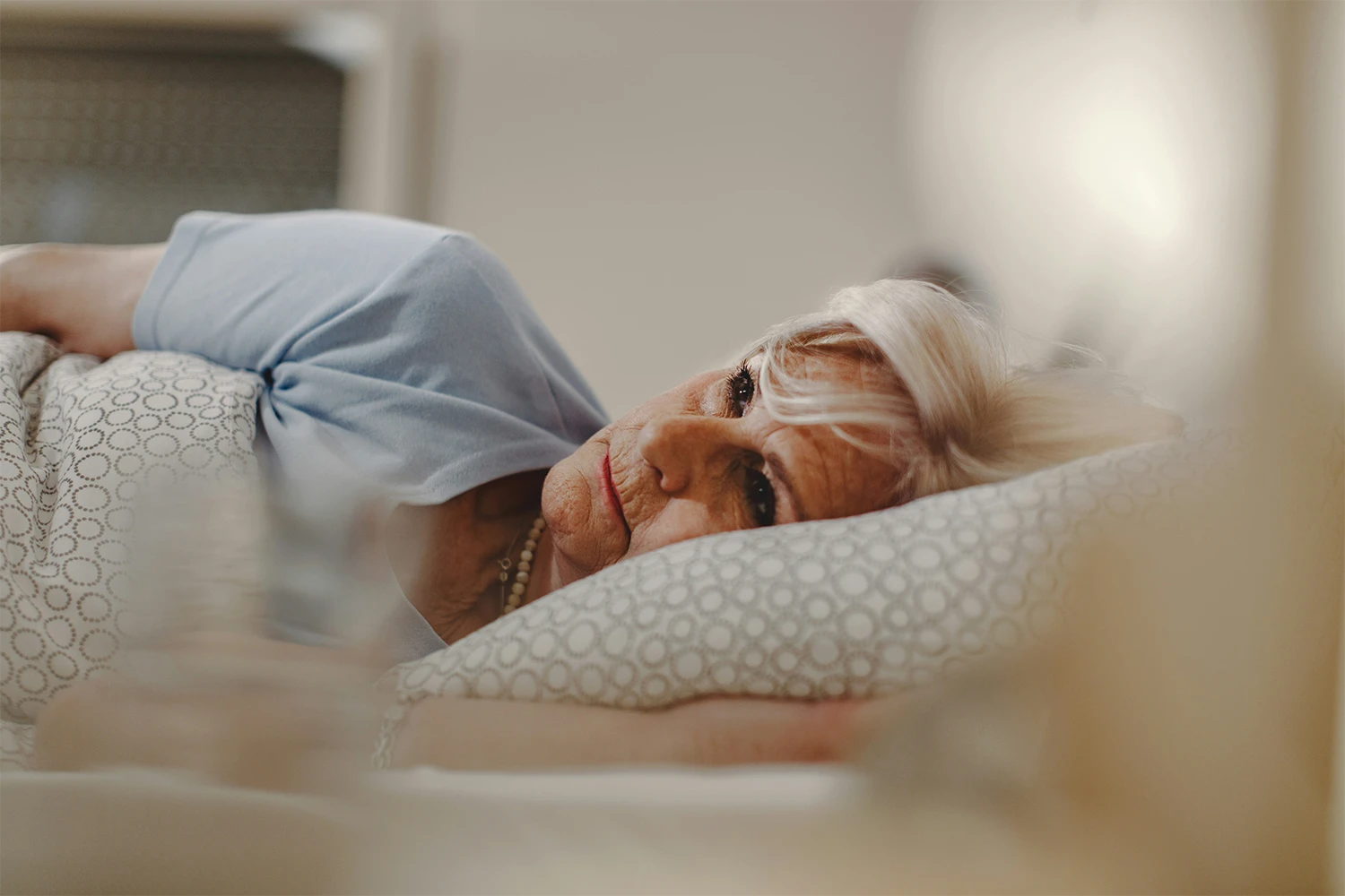 Ältere Frau leidet unter Schlafstörungen und liegt deshalb wach, schlaflos im Bett in der Nacht